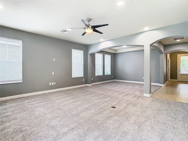 carpeted spare room featuring ceiling fan and plenty of natural light