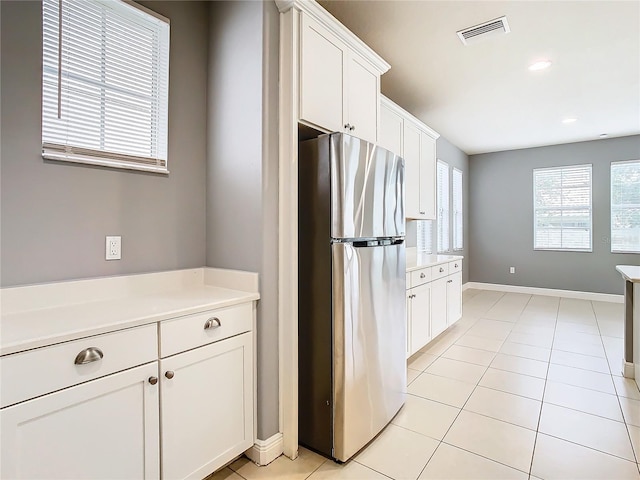 kitchen featuring stainless steel fridge, white cabinets, and light tile patterned flooring