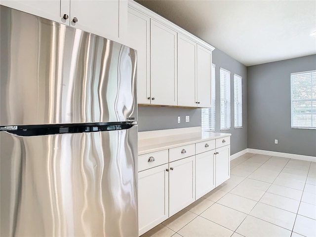 kitchen with white cabinets, stainless steel fridge, and light tile patterned floors