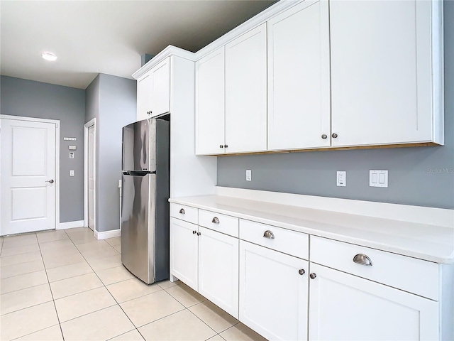 kitchen featuring stainless steel fridge, white cabinetry, and light tile patterned floors