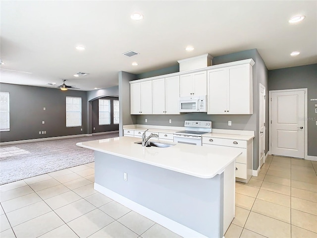 kitchen with white appliances, white cabinets, sink, an island with sink, and light tile patterned flooring