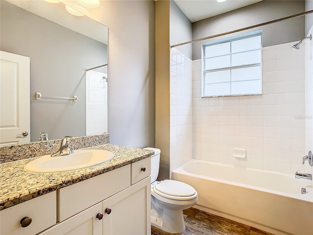 full bathroom with hardwood / wood-style floors, tiled shower / bath combo, toilet, and vanity