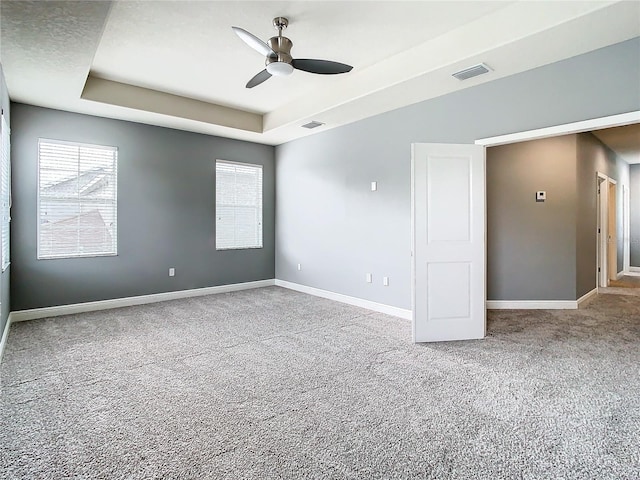 carpeted spare room featuring ceiling fan and a raised ceiling