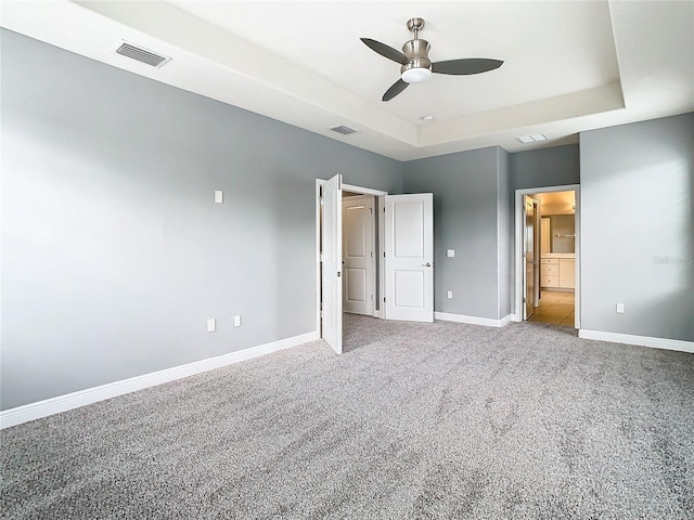 unfurnished bedroom featuring ceiling fan, carpet floors, and a tray ceiling