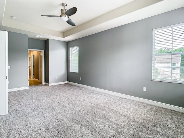 empty room with carpet, a raised ceiling, and ceiling fan