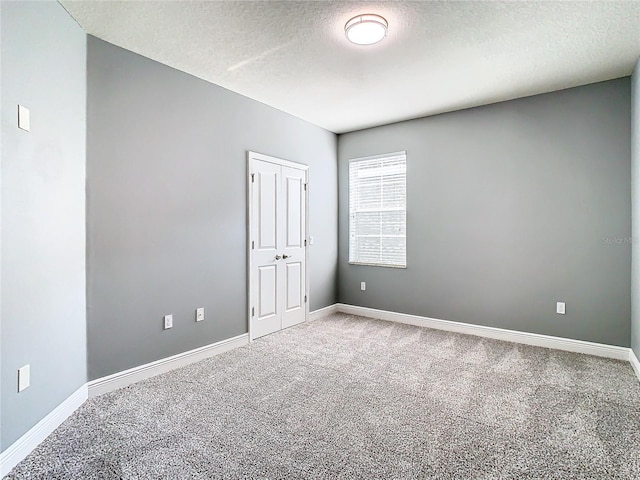 carpeted empty room featuring a textured ceiling