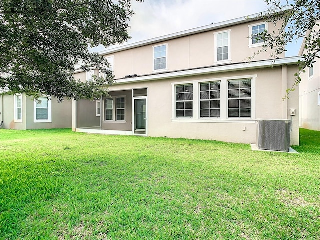 back of house with central AC unit and a lawn