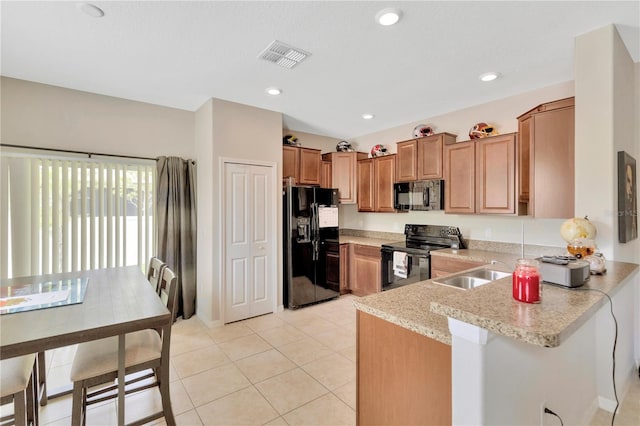 kitchen featuring black appliances, sink, light stone countertops, light tile patterned flooring, and kitchen peninsula