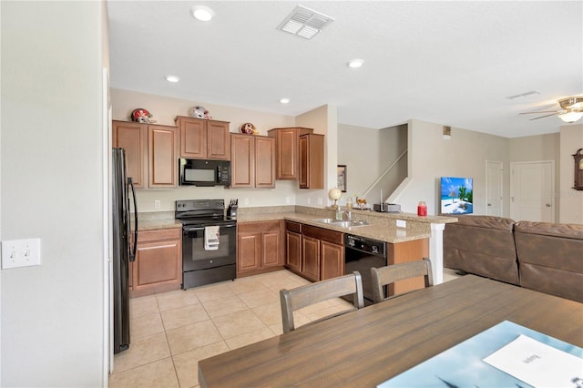 kitchen with black appliances, sink, light tile patterned flooring, light stone counters, and kitchen peninsula