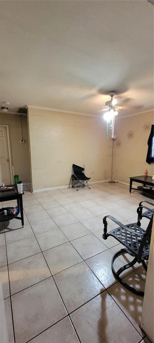 exercise room with ceiling fan, light tile patterned flooring, and crown molding