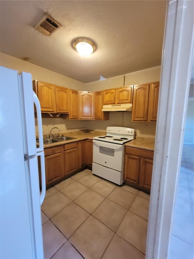 kitchen featuring white appliances, visible vents, light countertops, under cabinet range hood, and a sink