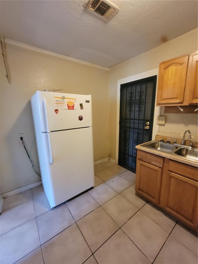 kitchen with light countertops, visible vents, freestanding refrigerator, a sink, and a textured ceiling