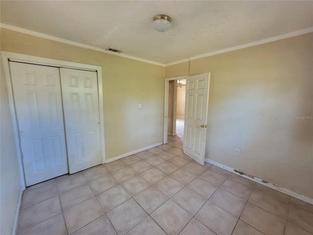 unfurnished bedroom featuring baseboards, visible vents, ornamental molding, a closet, and light tile patterned flooring