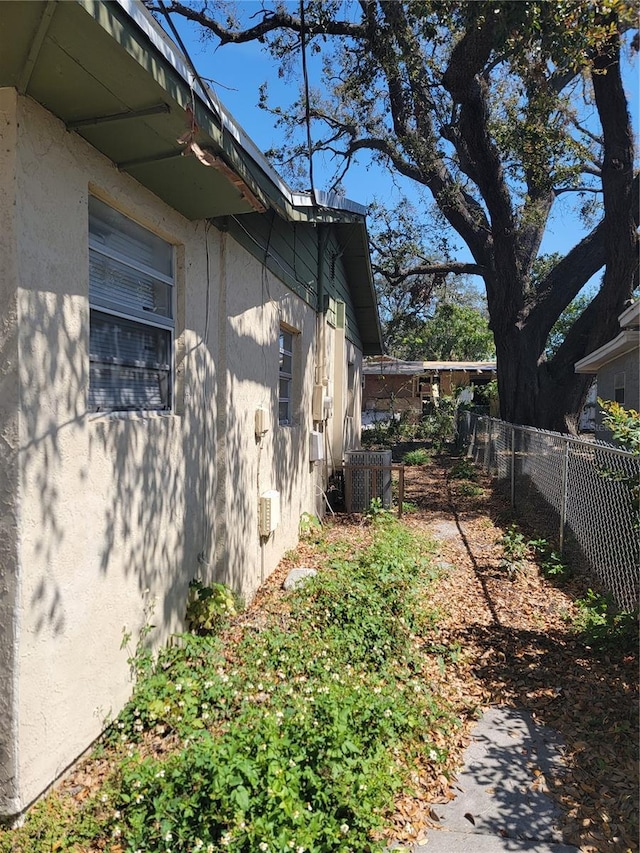 view of home's exterior featuring fence, cooling unit, and stucco siding