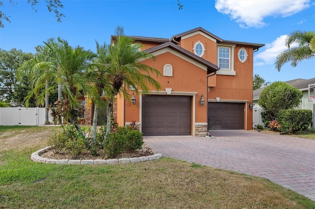 view of front facade with decorative driveway, stucco siding, a gate, fence, and a garage