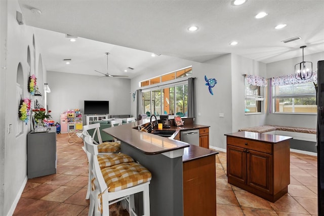 kitchen with dark countertops, a kitchen island, open floor plan, stainless steel dishwasher, and a sink