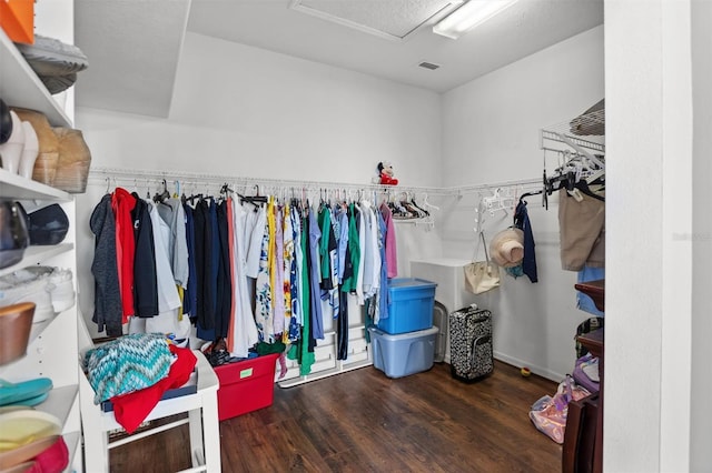 walk in closet with attic access and wood finished floors