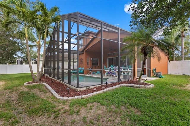 rear view of house featuring a fenced in pool, a yard, a patio, glass enclosure, and a fenced backyard