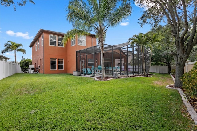 rear view of house featuring a yard, stucco siding, a fenced backyard, and a lanai