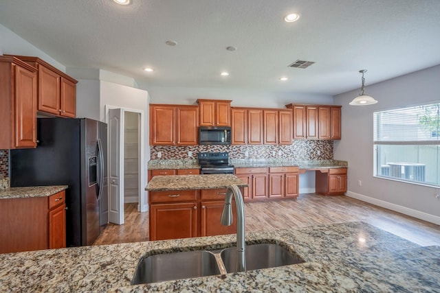 kitchen with light stone counters, stainless steel appliances, sink, and hanging light fixtures