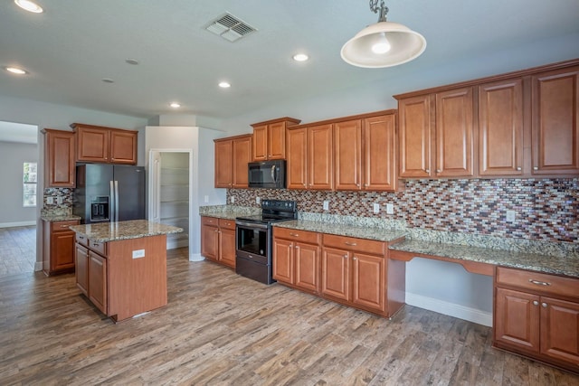 kitchen with a center island, stainless steel refrigerator with ice dispenser, range with electric stovetop, built in desk, and decorative light fixtures