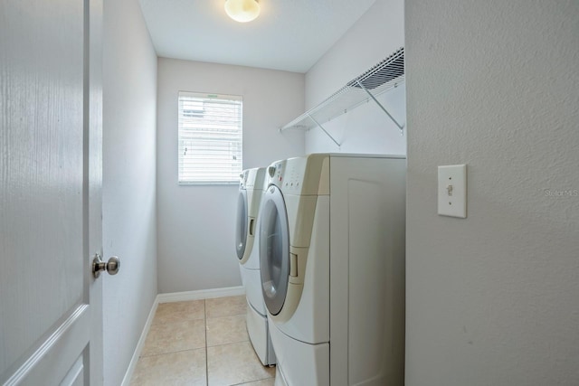 clothes washing area featuring light tile patterned flooring and washer and clothes dryer