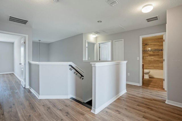 corridor with light hardwood / wood-style flooring and a textured ceiling