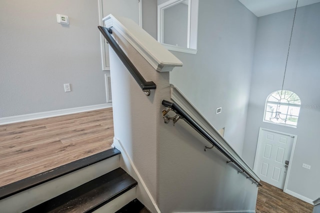 stairway with a towering ceiling and hardwood / wood-style floors