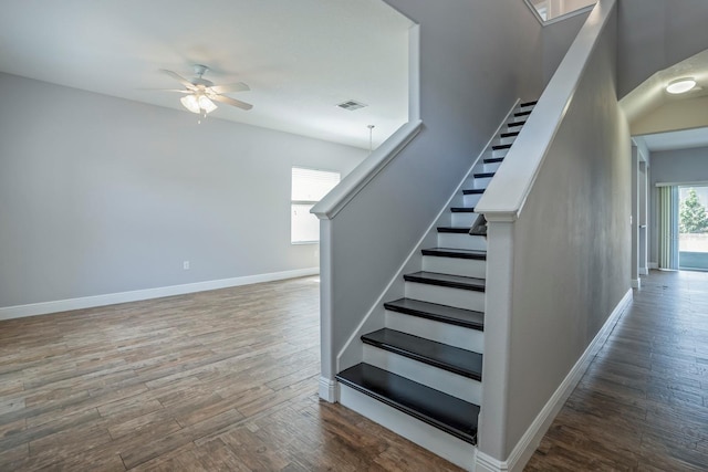 staircase featuring wood-type flooring and ceiling fan