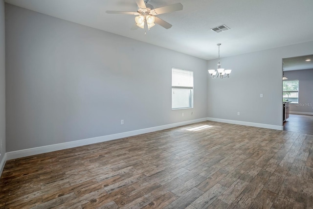 unfurnished room featuring plenty of natural light, dark hardwood / wood-style floors, and ceiling fan with notable chandelier