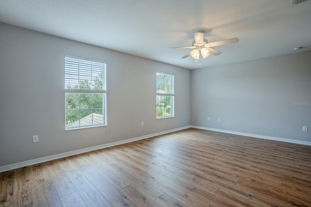 unfurnished room featuring ceiling fan, wood-type flooring, and a healthy amount of sunlight