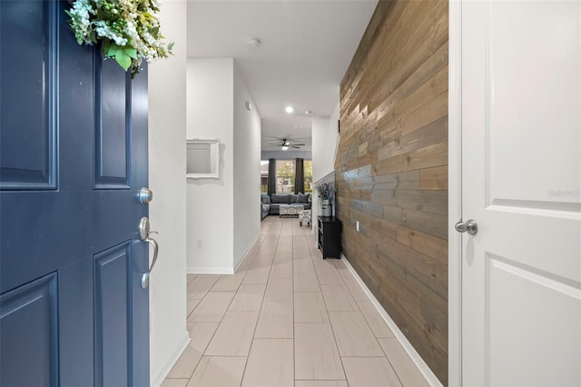 foyer entrance with ceiling fan and wooden walls