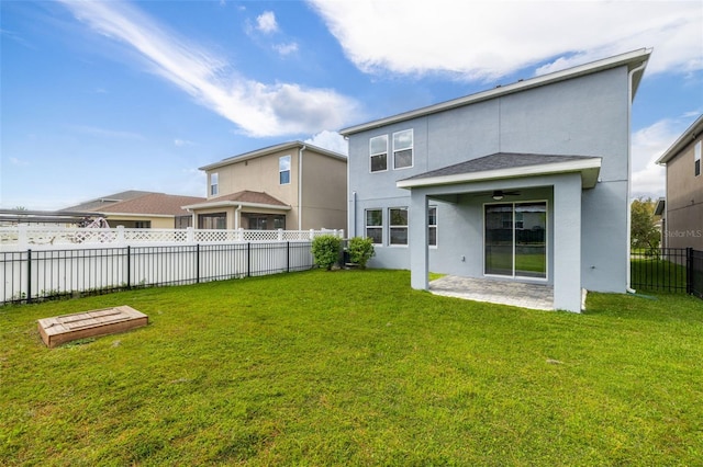 back of property featuring ceiling fan and a yard