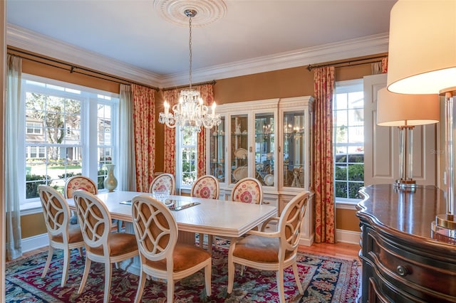 dining space with wood-type flooring, ornamental molding, and a notable chandelier