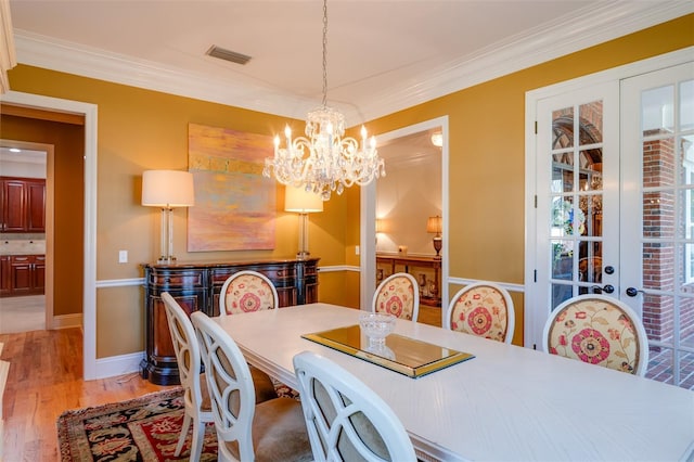 dining space featuring a notable chandelier, light wood-type flooring, and crown molding