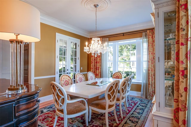 dining space featuring an inviting chandelier, wood-type flooring, ornamental molding, and french doors