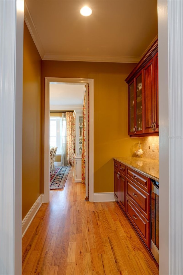 hallway with light wood-type flooring and crown molding