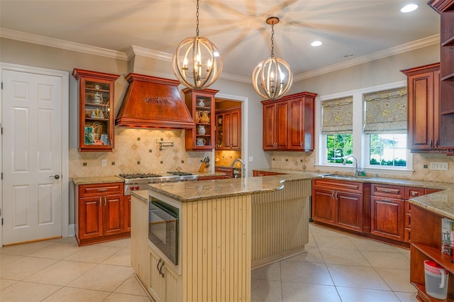 kitchen featuring sink, a kitchen island with sink, hanging light fixtures, a notable chandelier, and decorative backsplash