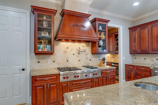 kitchen with sink, light stone counters, stainless steel gas stovetop, decorative backsplash, and custom exhaust hood