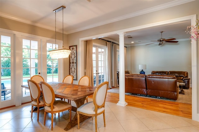 tiled dining space with ceiling fan with notable chandelier, ornate columns, crown molding, and french doors