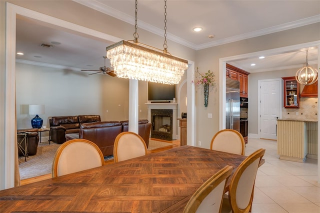 dining space featuring ceiling fan with notable chandelier, light tile patterned floors, and crown molding