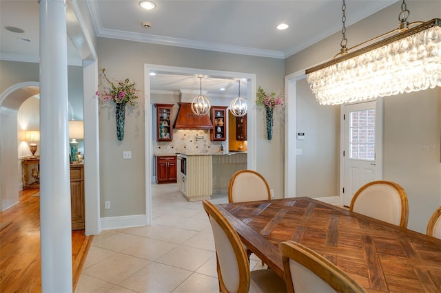 tiled dining space featuring crown molding and an inviting chandelier