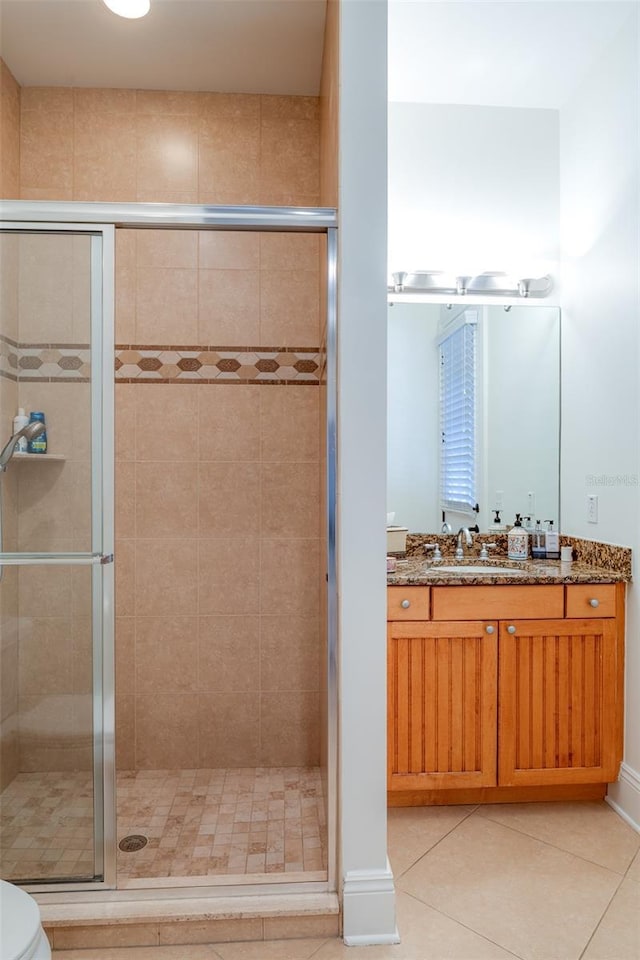 bathroom with tile patterned floors, toilet, vanity, and walk in shower