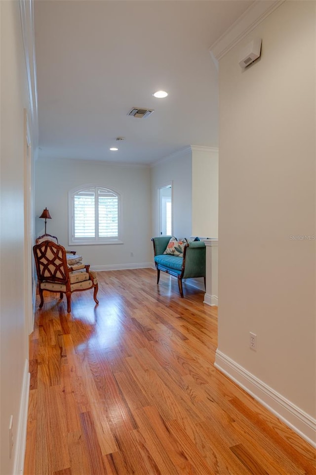 living area with light hardwood / wood-style flooring and ornamental molding