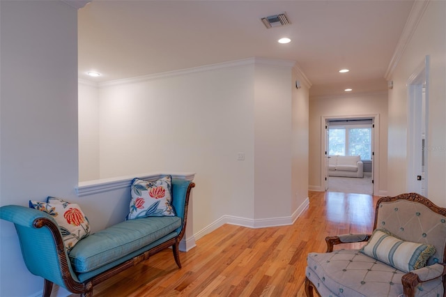 sitting room featuring ornamental molding and light wood-type flooring