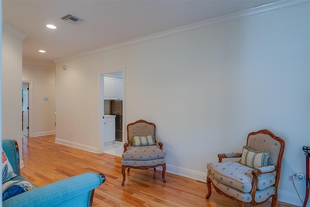 sitting room featuring light wood-type flooring and crown molding