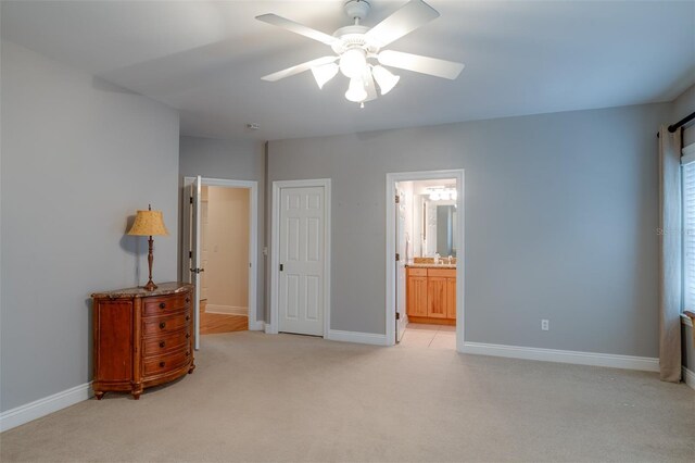 unfurnished bedroom with ceiling fan, a closet, light colored carpet, and ensuite bath