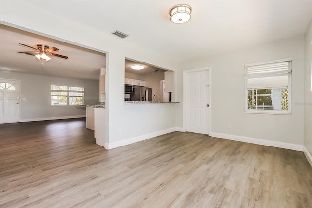 unfurnished living room featuring ceiling fan and light hardwood / wood-style floors