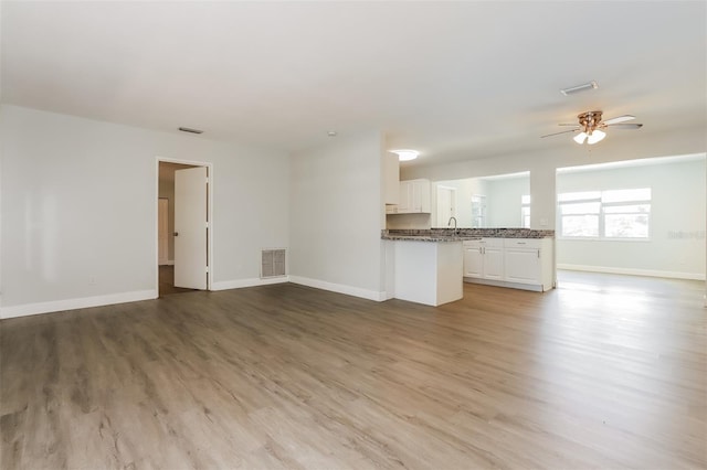 unfurnished living room with ceiling fan, light wood-type flooring, and sink