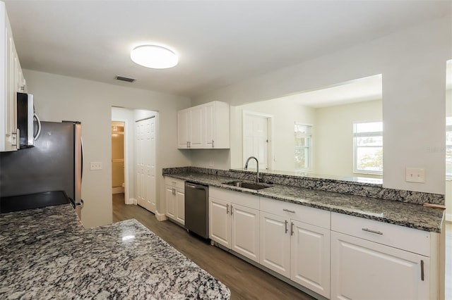 kitchen with white cabinets, stainless steel appliances, dark stone counters, and sink